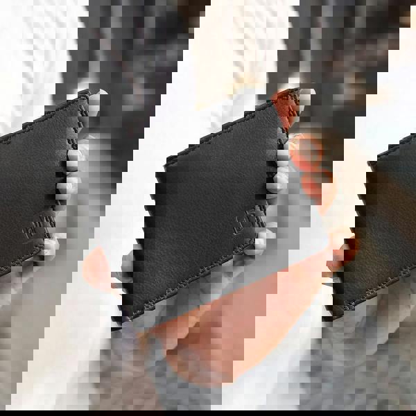 Hand holding a black leather wallet with a brand logo.