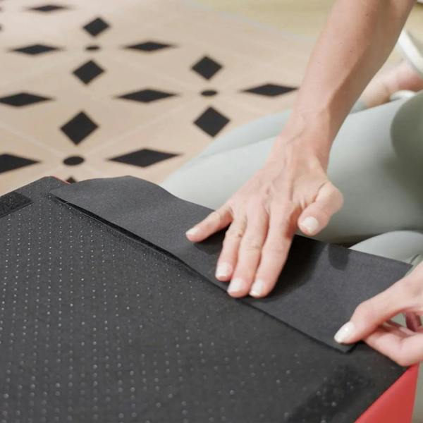 Hand smoothing black foam cover on red-edged climbing block, easy-clean PU material