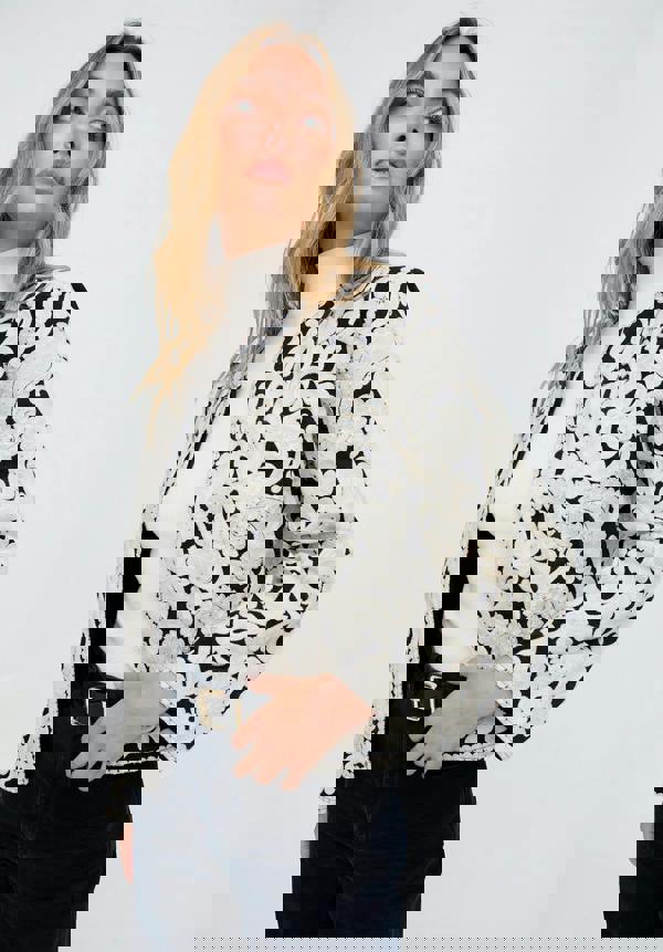 Woman wearing a black and white floral lace jacket on a white background