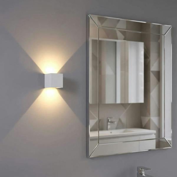 white modern bathroom wall light mounted on the wall next to a bathroom mirror 