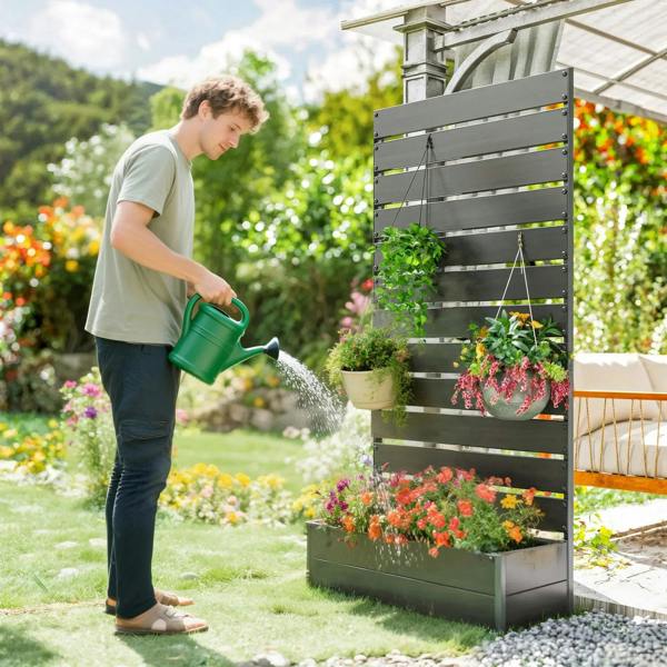 Black tall trellis planter box with colorful flowers, watered with a green can