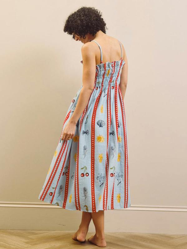 Woman wearing a colorful nightie dress with a pattern against a beige wall.