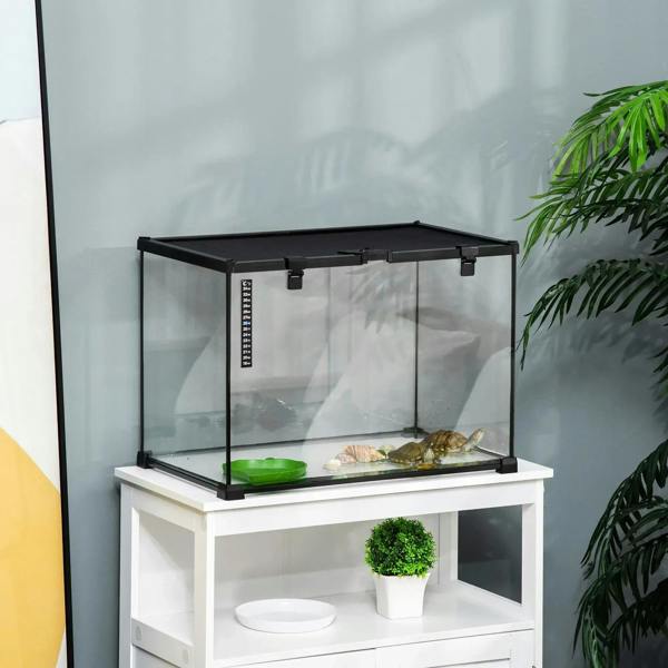 Black framed glass reptile terrarium on white stand with green water basin and thermometer