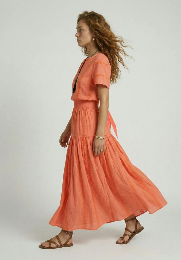 Woman wearing a coral dress with a plain background