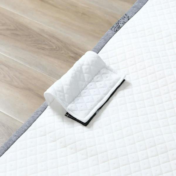 Close-up of white quilted mattress pad folded on a gray folding bed base edge