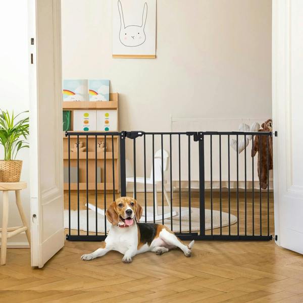 Black safety gate with vertical bars pressure-mounted in doorway, dog lying down