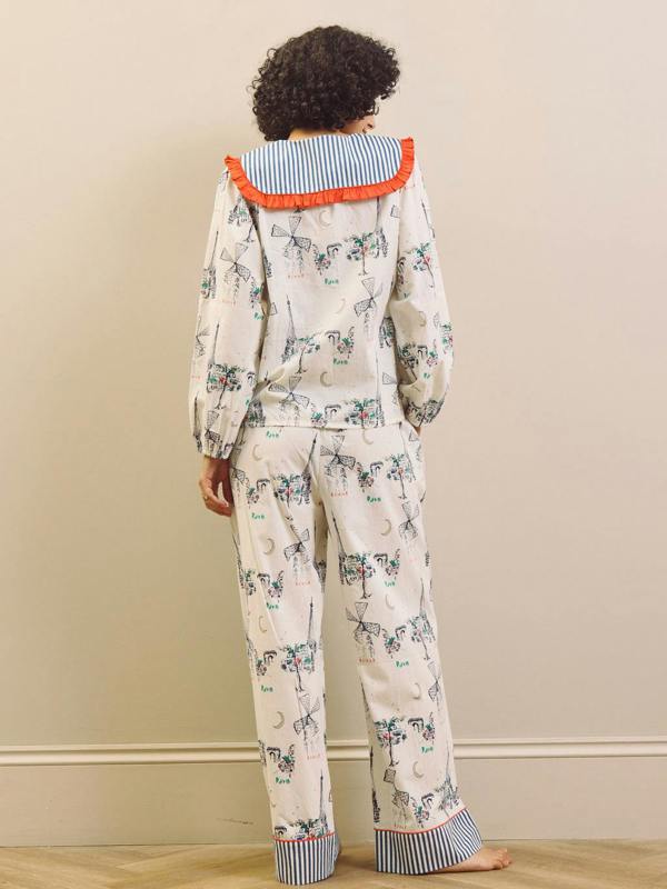 Woman wearing a Paris themed printed pyjama set with a large collar with red frill against a beige background