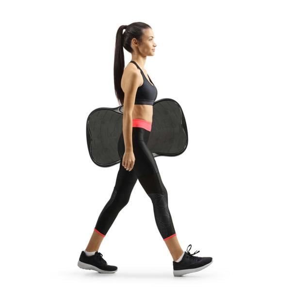 A woman in athletic wear carries a Whole Body Vibration Training Exercise Plate on her back, walking right against a white background, ready for a full body workout.