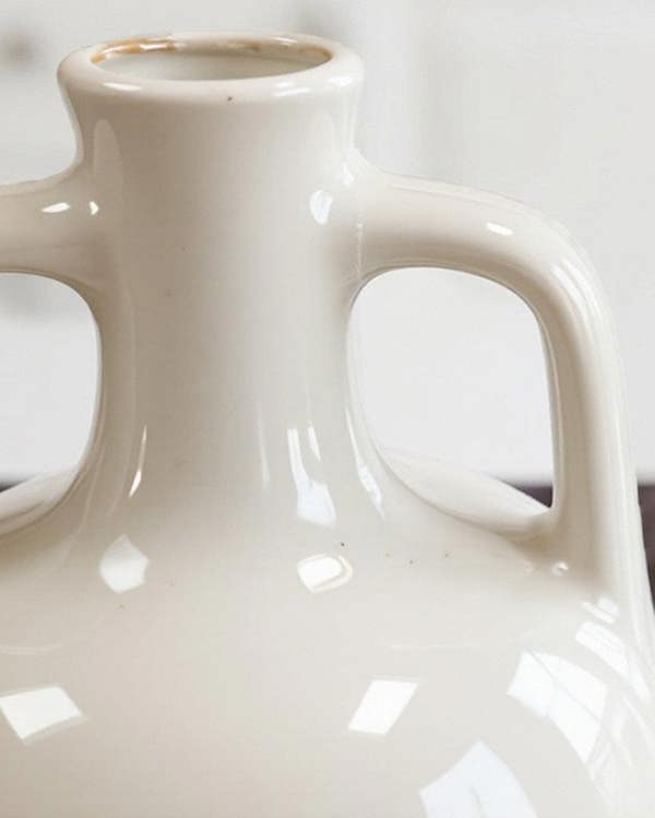 White ceramic vase on a marble surface with a blurred background