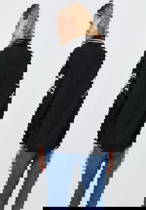 Black jacket with white palm tree designs on sleeves, worn by a person against a light gray background