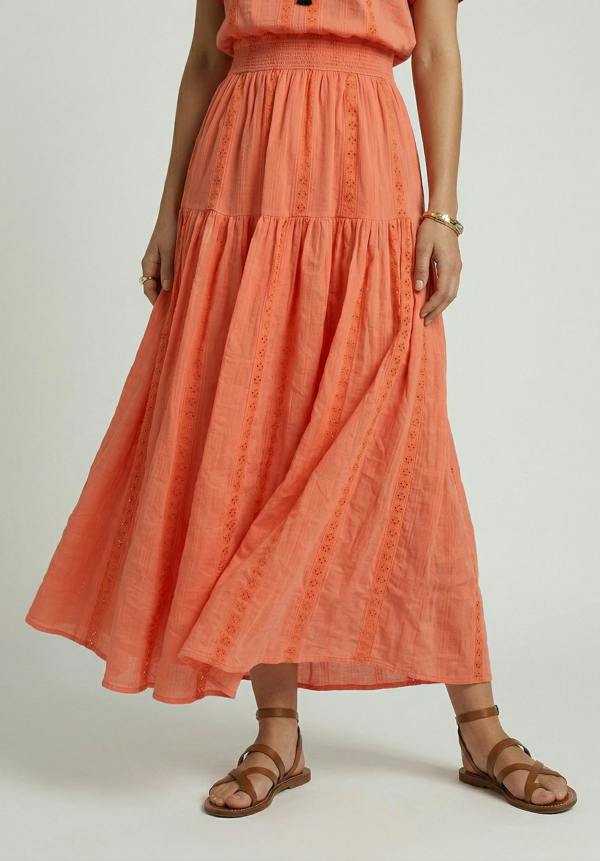 Person wearing a coral dress with a plain background