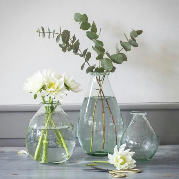 Three recycled glass teardrop vases in different sizes styled with white dahlias and eucalyptus on a rustic table