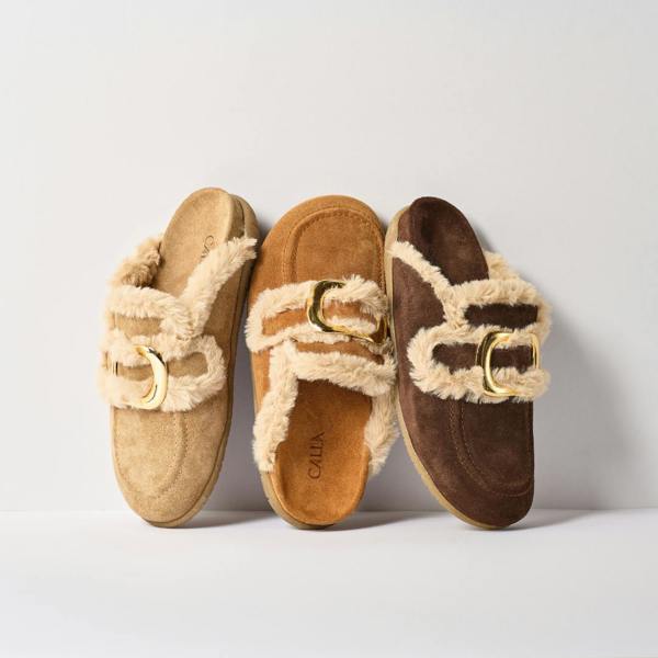 Three pairs of slippers with fur trim and gold buckles on a light background