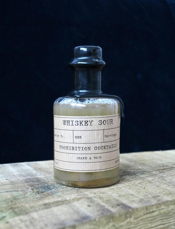 Bottle of Prohibition Cocktails Whiskey Sour on a wooden surface with a dark background