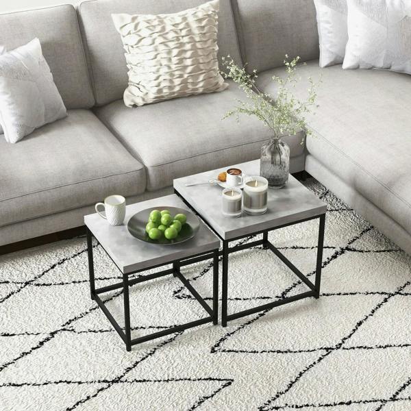 Grey two-piece nesting coffee table set on a rug with framed decor and candles