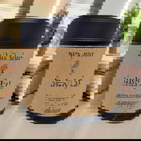 Candle labeled 'Smoky Earl' by Ralph's Orchard on a surface with a blurred background