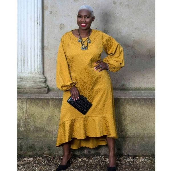 Women's Plus Size Gold Aphrodite Leopard Jacquard Dress styled with a yellow stone necklace, black clutch, and black heels for an elegant look.