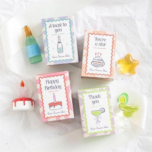 Set of glass celebration charms with candle, star, bottle and cocktail glass shapes.