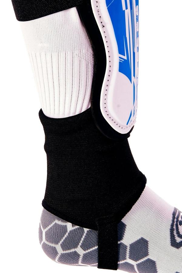 Blue and white Optimum Velocidade shin guard with black ankle sock and foot strap on lower leg, close-up on white - Optimum