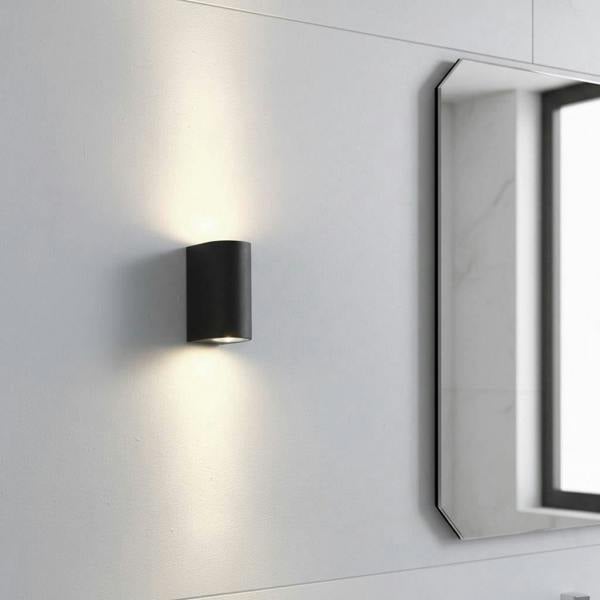 black bathroom wall mount light fitting shown on a wall next to a mirror in a bathroom
