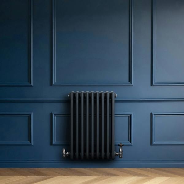 Traditional anthracite grey 4 column radiator with valves, mounted on a deep blue wall, featuring sleek vertical lines and a modern design