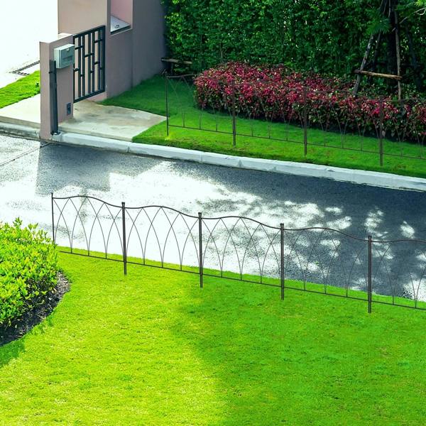 Black decorative metal fence panels installed along a garden border with arched panels
