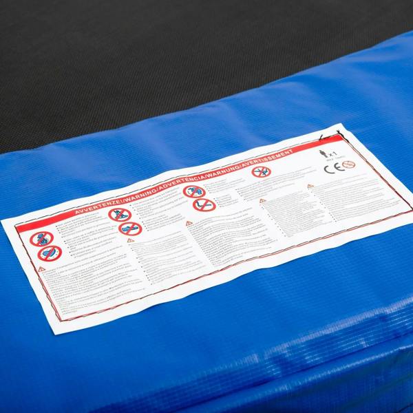Blue trampoline pad with white safety label on textured foam surface
