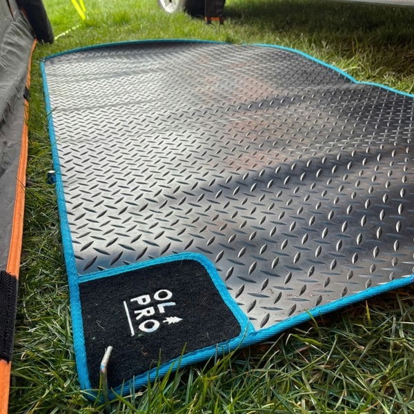 OLPRO Awning Tunnel Mat 1500mm x 800mm Black Rubber with Blue Edge Trim being used within a camper van awning in-between the awning tunnel and campervan.