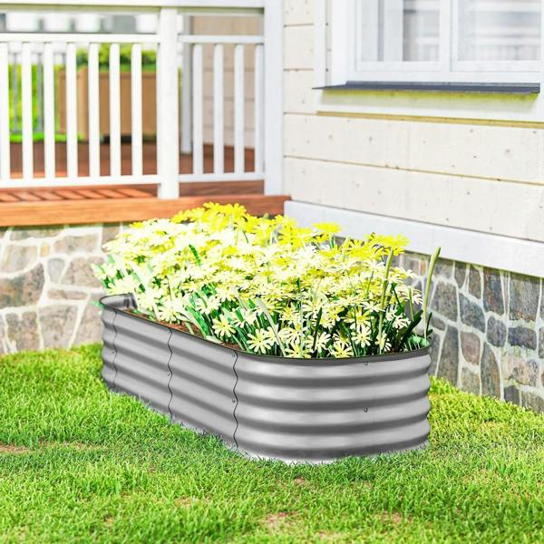 Gray galvanized metal raised garden bed with herbs and small plants on grass