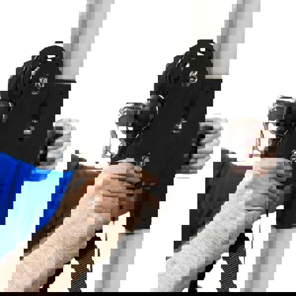 Wall mounted cable pulley machine with a black pulley system, adjustable strap, and a hand gripping the mechanism for easy use