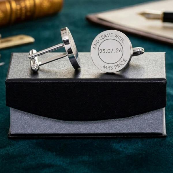 pair of personalised silver round cufflinks engraved with a wedding date and the words "And leave with... Mrs Price" resting on a black gift box.