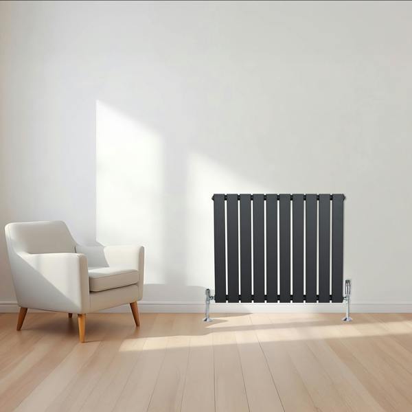 Flat single column radiator in anthracite grey, featuring vertical slats, sleek design, and positioned beside a modern armchair in a bright room