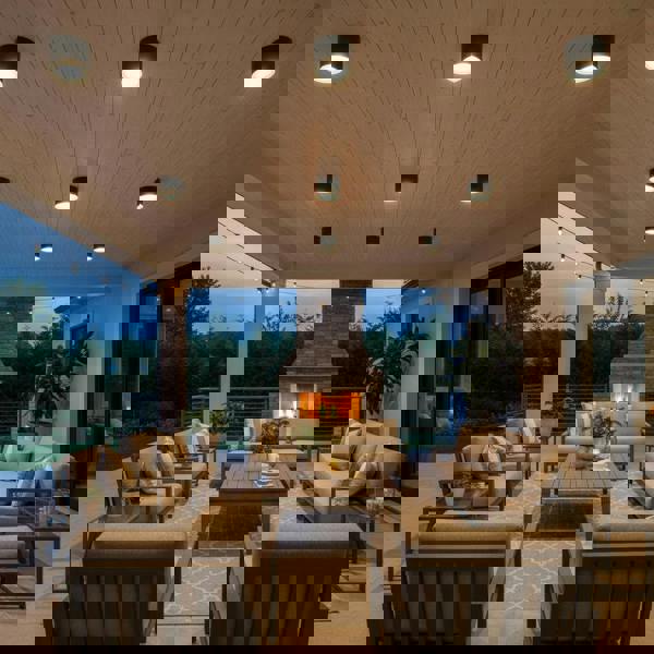 black waterproof outdoor downlight mounted on the ceiling of an outside seating area