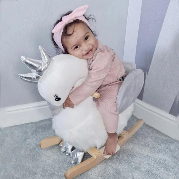Child riding plush white swan rocker with grey seat and wooden rockers