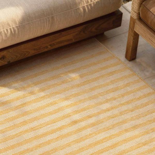 Striped yellow and beige rug on a wooden floor with a wooden chair and sofa.