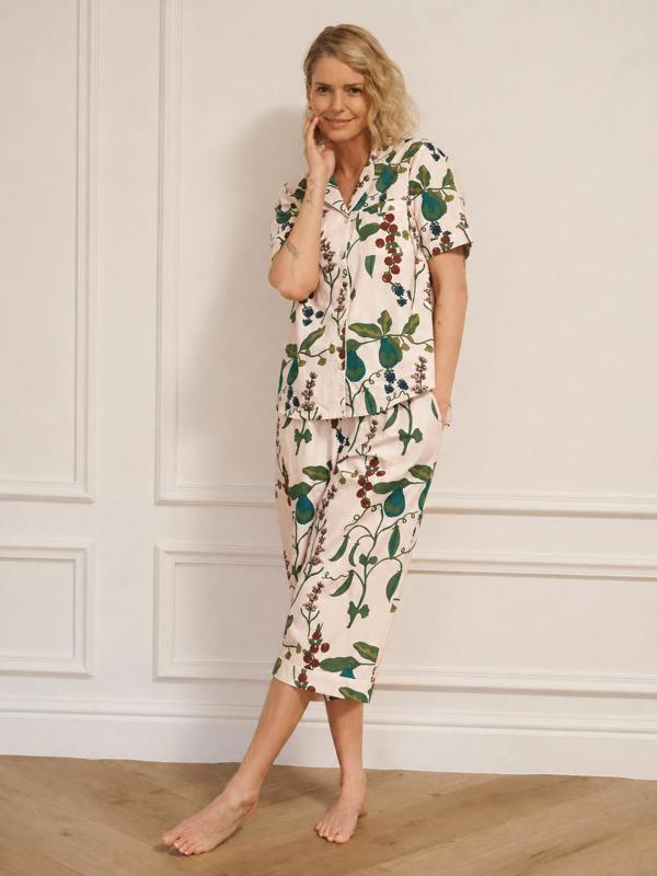 Woman wearing a floral pyjama set against a white wall.