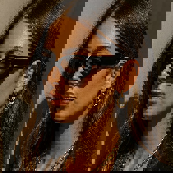 Woman wearing sunglasses and a black leather jacket against a neutral background