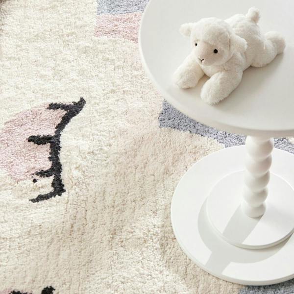 White teddy bear on a white stool next to a textured rug with abstract patterns