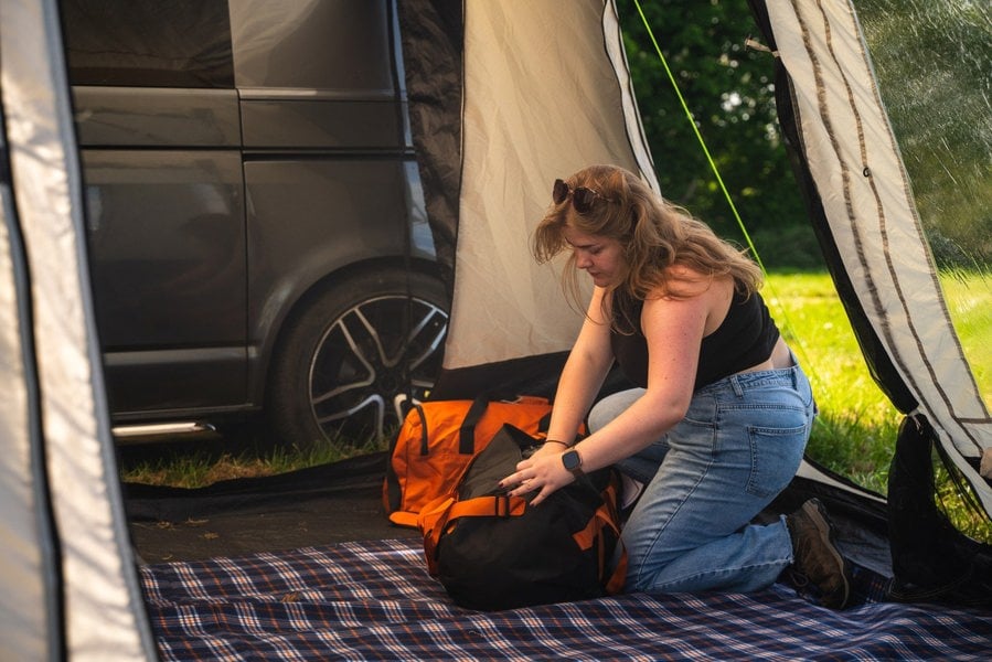 A young woman packs her OLPRO rucksack inside a Cubo  Poled Campervan Awning