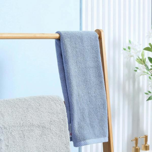 Blue towel hanging from the top bar on a bamboo freestanding towel rack
