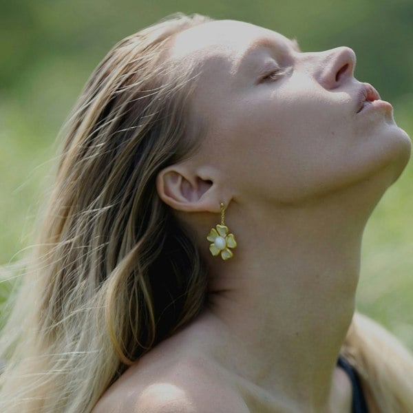 A face of a beautiful model wearing gold vermeil floral drop earrings.