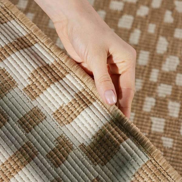 Hand touching a textured brown and beige checkered fabric