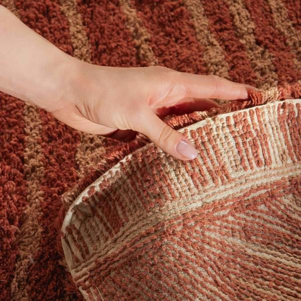 Hand touching a textured brown and beige fabric