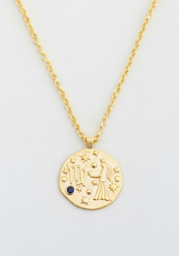 Gold necklace with a circular pendant featuring astrological design on a light gray background