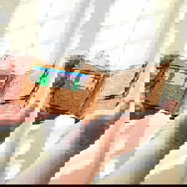 A man showcasing his Natural Cork Billfold Wallet filled with money.