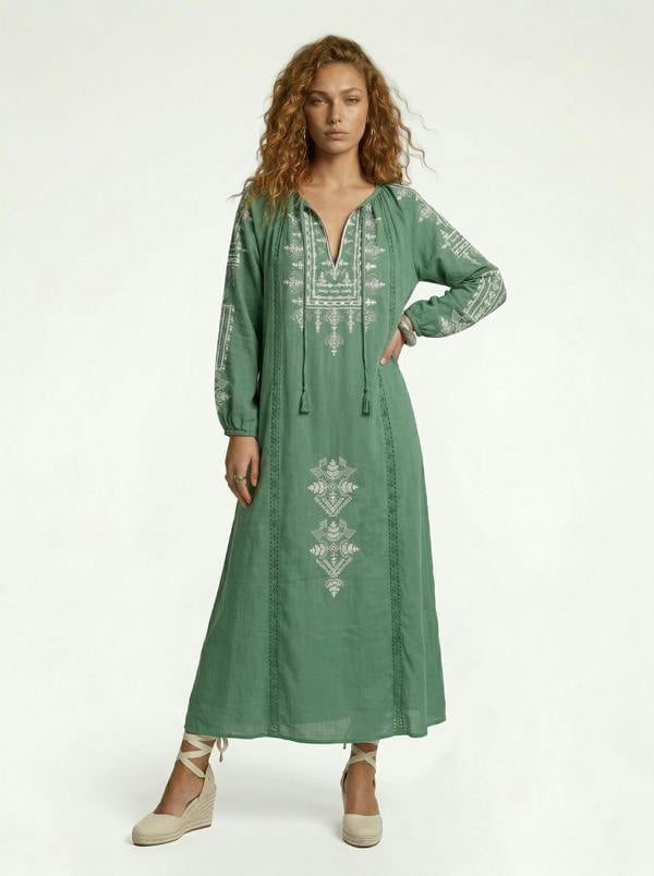 Woman wearing a green embroidered dress on a white background