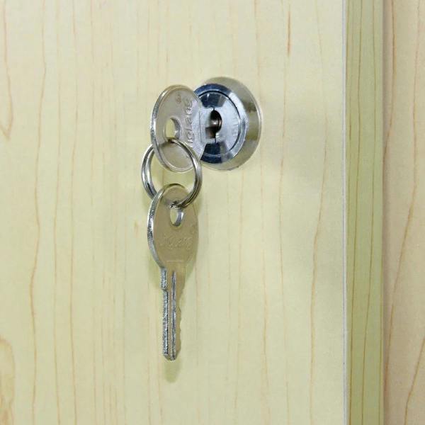 Close-up of a silver key inserted into a round lock on a maple-glazed display counter, showcasing the smooth wood grain finish
