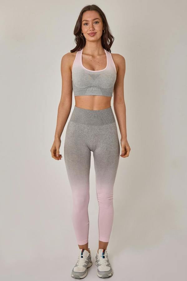 Woman wearing a gray sports bra and pink leggings on a plain background