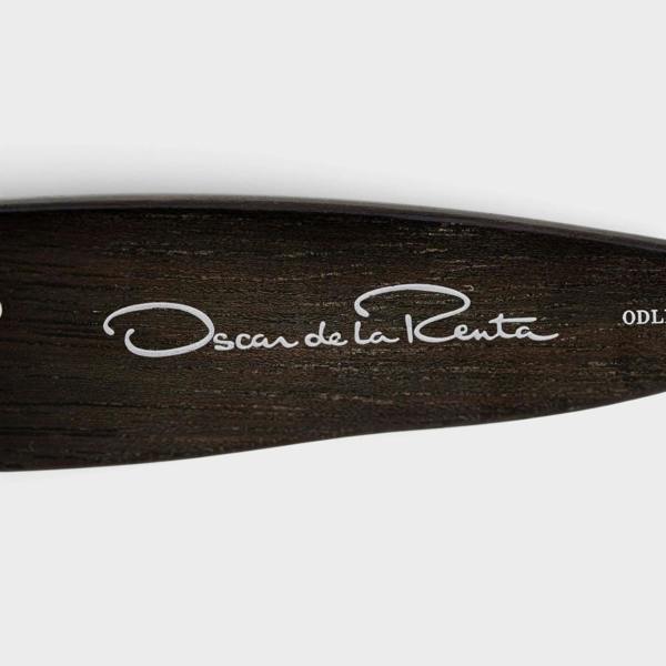 Supplied Fashion Linda Farrow oversized sunglasses temple detail featuring the Oscar de la Renta logo on dark wood grain