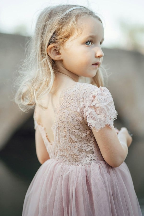 Young girl wearing a pink lace dress with a blurred background